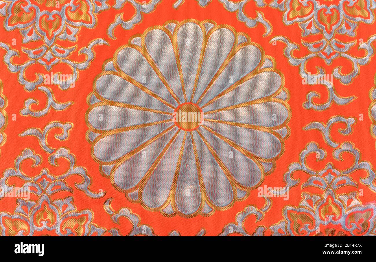 Texture of a silver and orange embroidered textile of chrysanthemum
