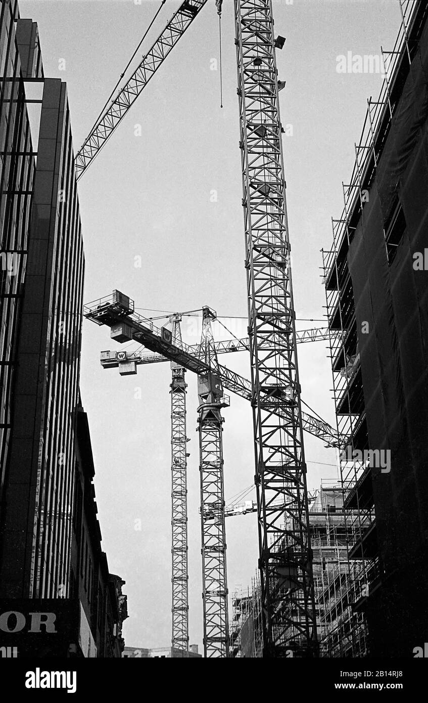 Cranes at work on high-rise buildings, Admiralitätstraße and Ludwig-Erhard-Straße, Hamburg, Germany, circa 1988.  Black and white film photograph Stock Photo