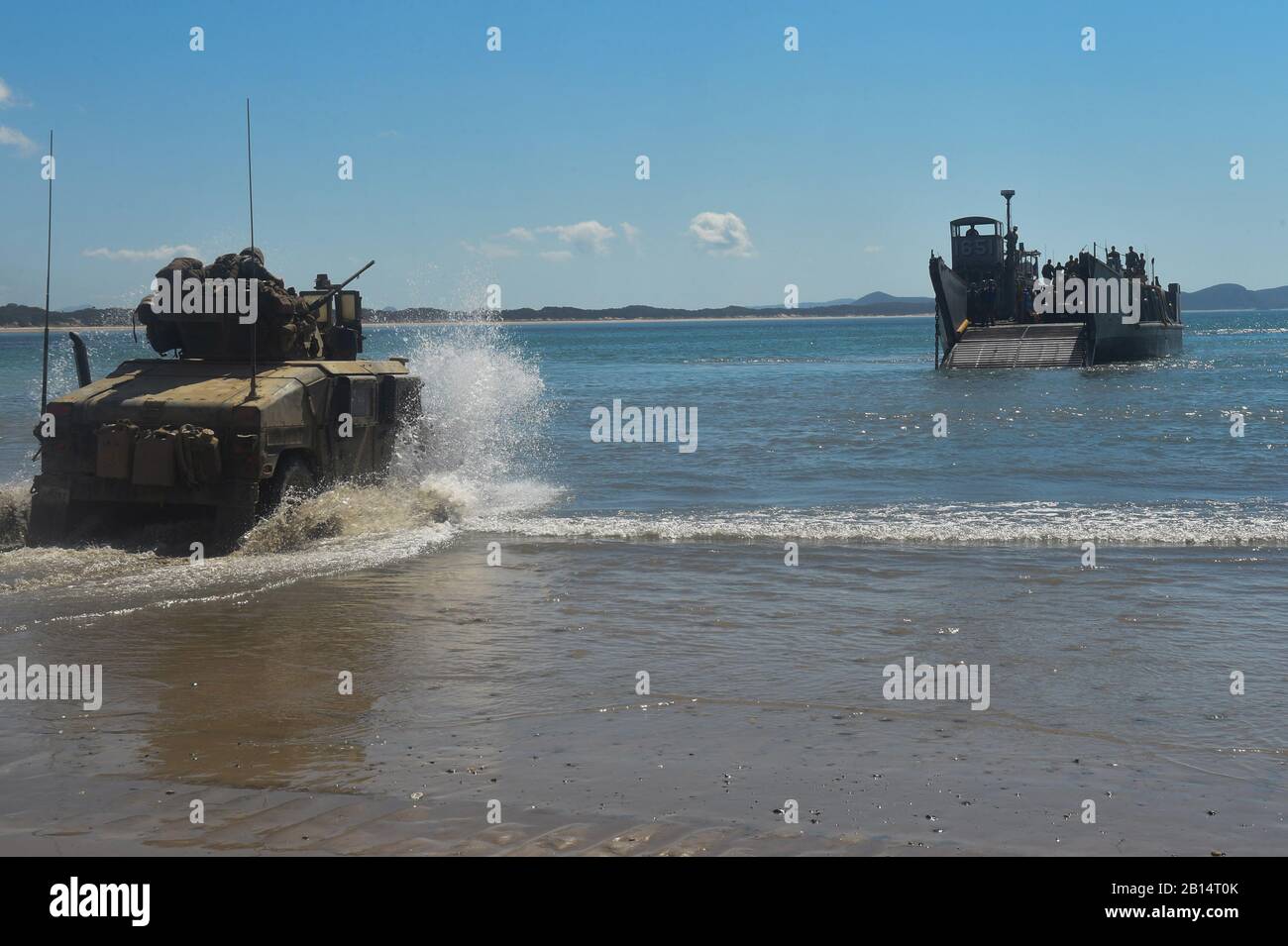 A U.S. Marine Corps Humvee enters the beach to board a Landing Craft Utility (LCU) 1651 in order to transfer personnel and equipment to the amphibious dock landing ship USS Ashland (LSD 48) after completion of certification exercise (CERTEX) in the Coral Sea, August 18, 2017. The Ashland, part of the Bonhomme Richard Expeditionary Strike Group (BHR ESG), and the 31st Marine Expeditionary Unit (MEU), participated in CERTEX to increase joint capability to respond to a number of potential contingencies. CERTEX was conducted to evaluate the integration of all elements of the BHR ESG testing their Stock Photo