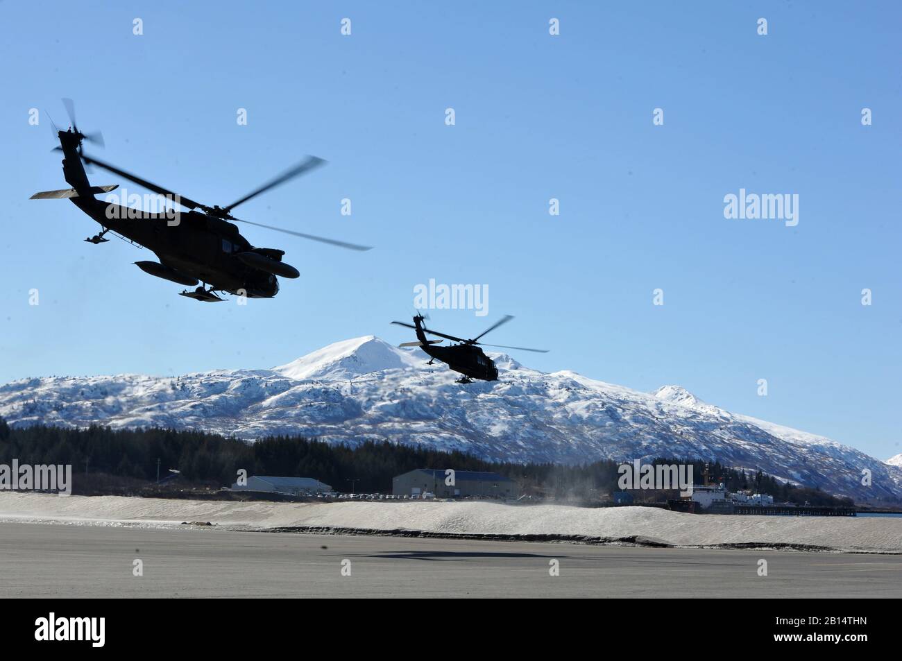 Two U.S. Army UH-60 Black Hawk helicopters assigned to the Alaska National Guard’s 1st Battalion, 207th Aviation Regiment launch toward villages on Kodiak Island as part of the Arctic Care 2017 medical readiness training, March 28, 2017, at Coast Guard Air Station Kodiak, Alaska. Arctic Care 2017 is an Office of Secretary of Defense sponsored, Air Force Reserve Command led, training event coordinated with Kodiak Area Native Association and civil authorities in Kodiak. (U.S. Air Force photo by Master Sgt. Luke Johnson) Stock Photo