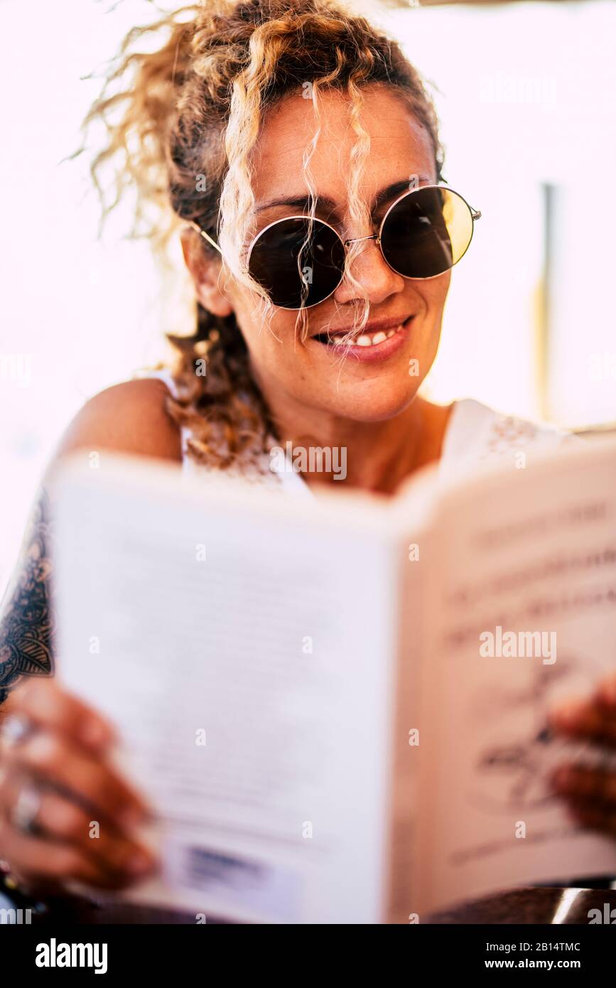 Beautiful caucasian young 40 years old woman read a paper book outdoor - relax and study or enjoy reading - cheerful happy people and bookstore concep Stock Photo