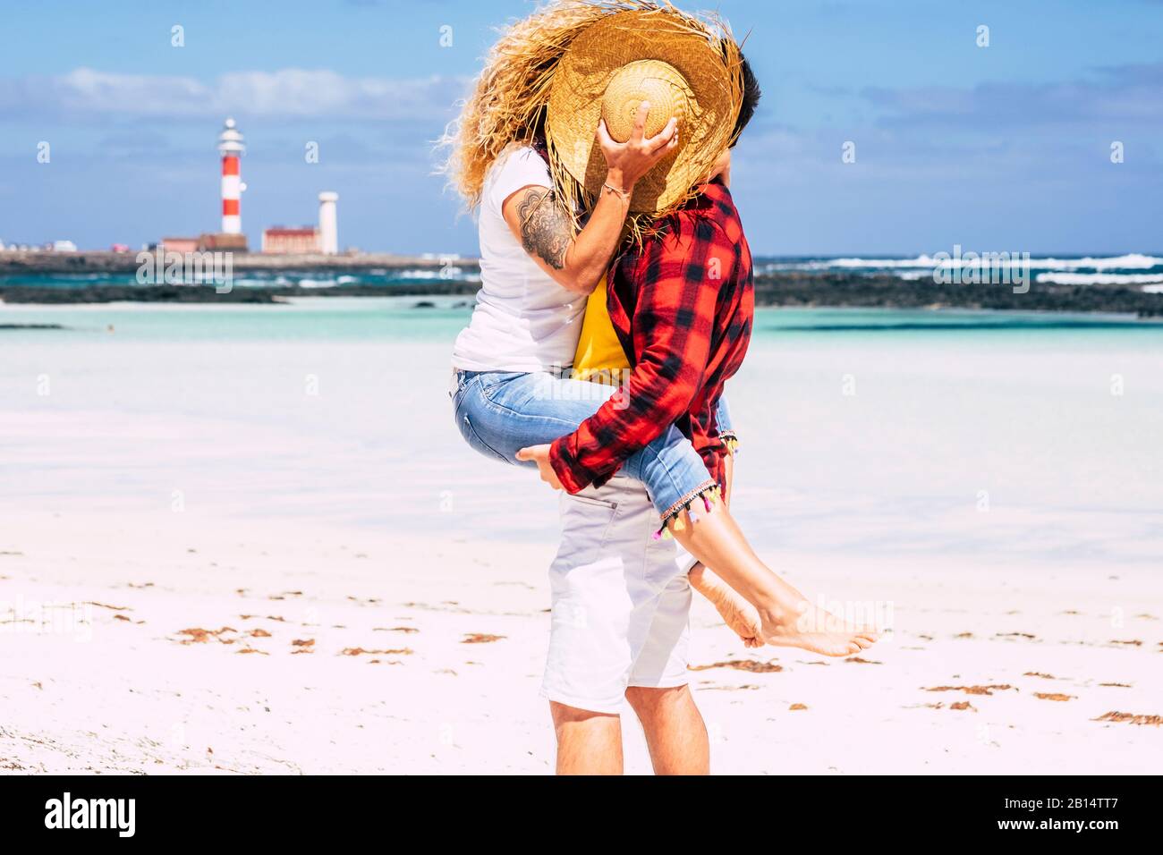 Couple kissing with love - concept of summer holiday vacation or honeymoon for people in relationship - background with beach and blue ocean and sky - Stock Photo