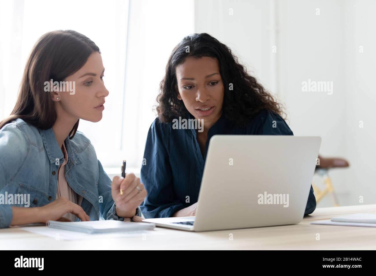Focused successful mixed race female entrepreneurs discussing project. Stock Photo