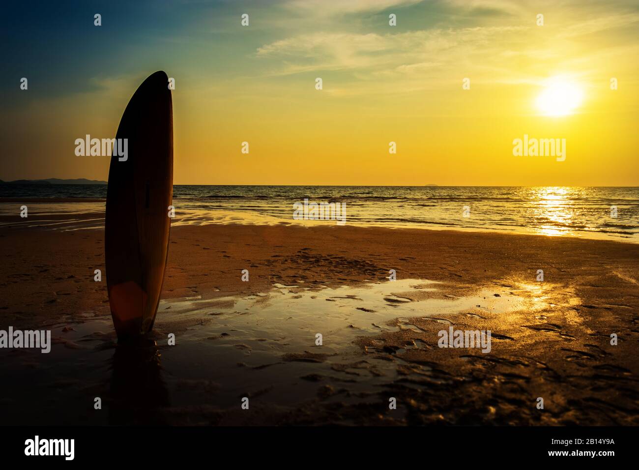 Surfing for water sport outdoor activity lifestyle concept. Silhouette of surfboard on the beach in sea shore at sunset time with beautiful light. Stock Photo