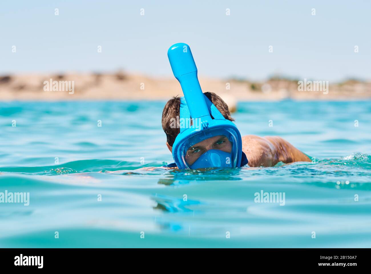 Man with snorkel full face mask diving in blue sea. Summer vacation Stock Photo