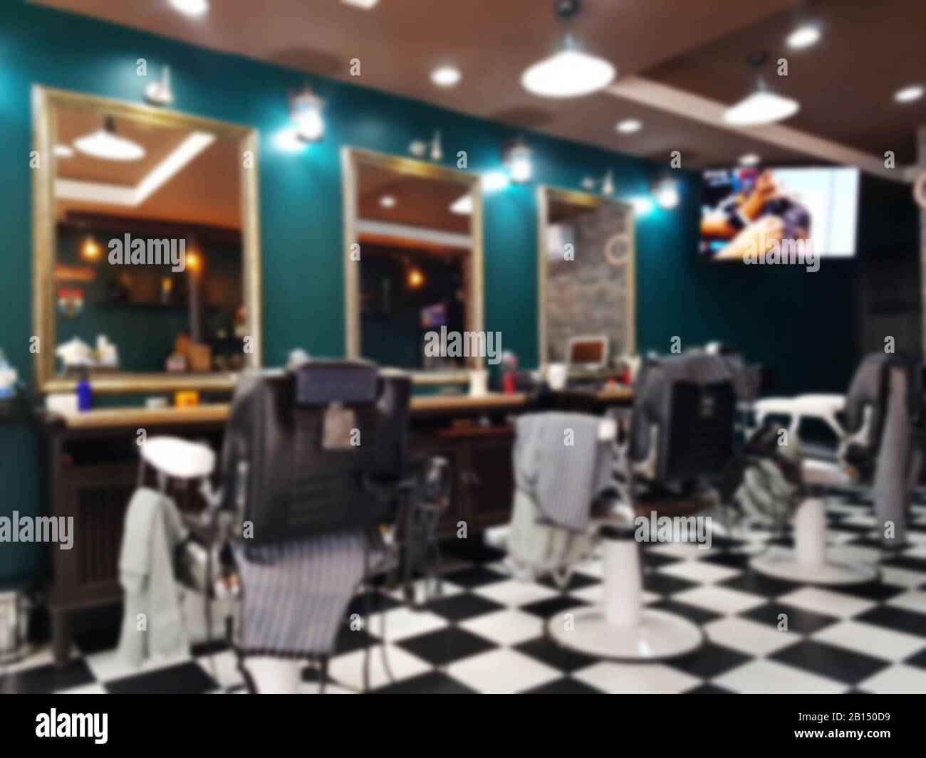 Interior of a beauty and hair salon blurry background concept. Row of black leather chairs in modern barber shop interior. Stock Photo