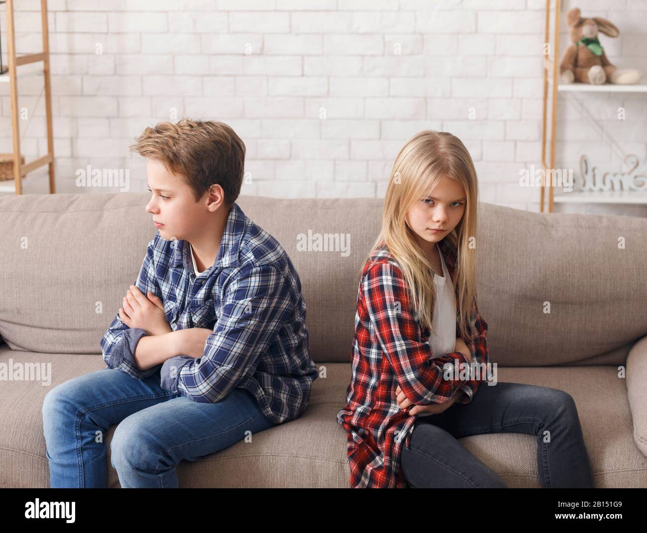 Brother And Sister Not Talking After Quarrel Sitting On Couch Stock Photo