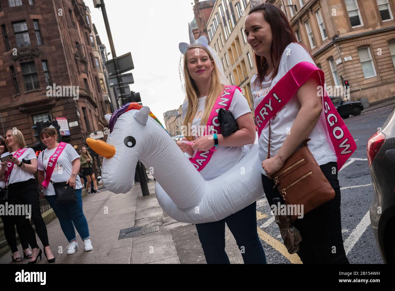 Glasgow, Scotland/UK, June 29, 2019: A bride, wearing a unicorn head piece with a veil and unicorn floatation device, walks the streets of Glasgow wit Stock Photo
