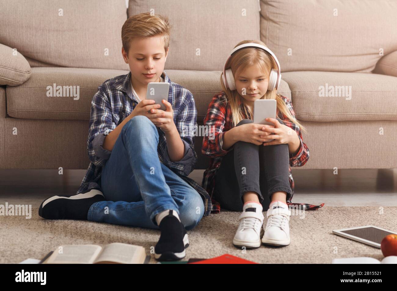 Siblings Using Mobile Phones Playing Games Sitting On Floor Indoor Stock Photo