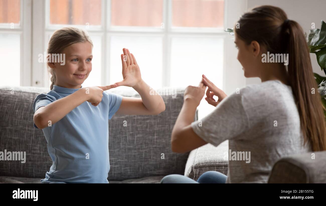 Smiling happy adorable girl communicating nonverbal with deaf dumb mother. Stock Photo