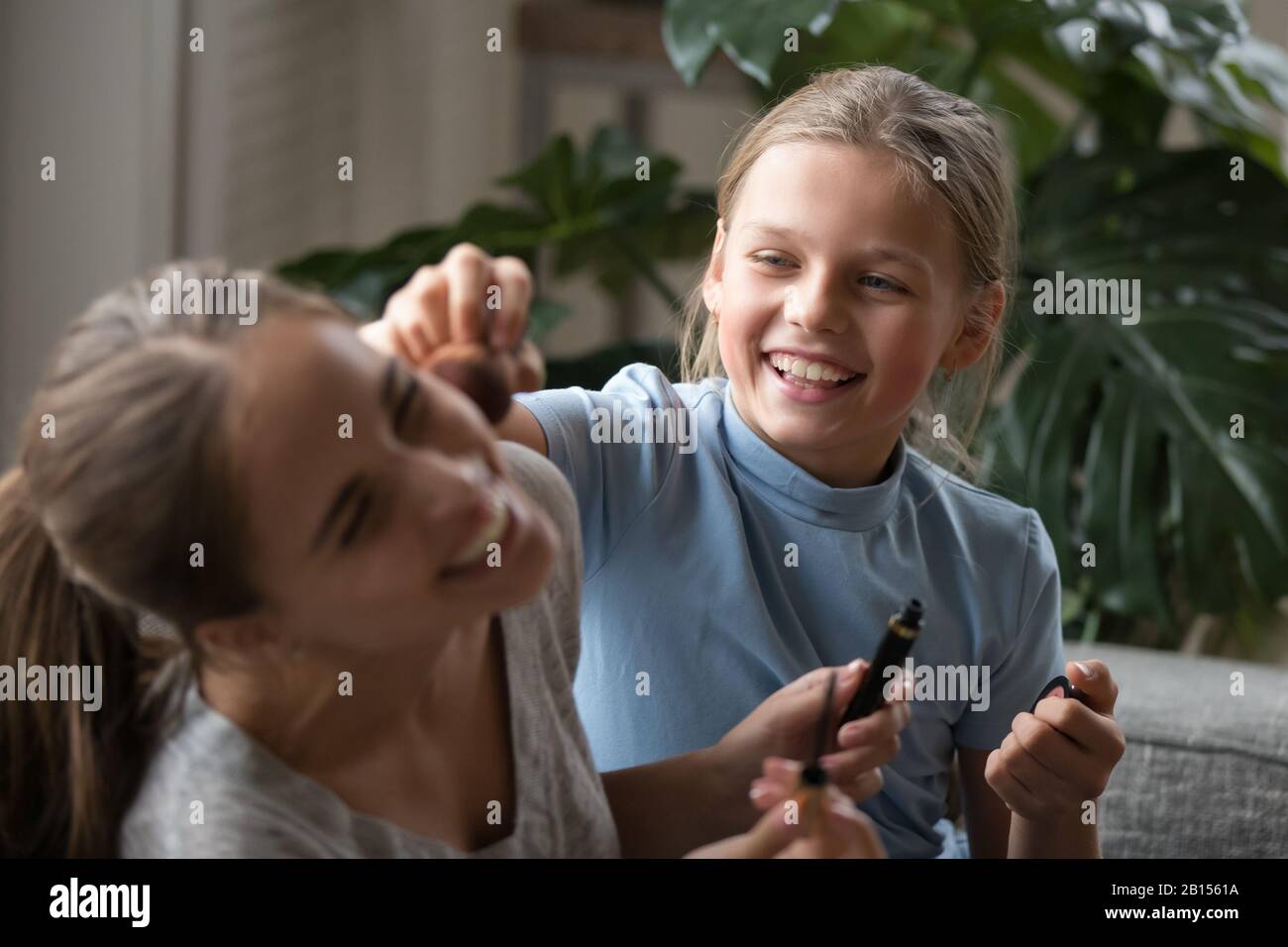 Close up overjoyed school age girl playing with decorative cosmetics. Stock Photo