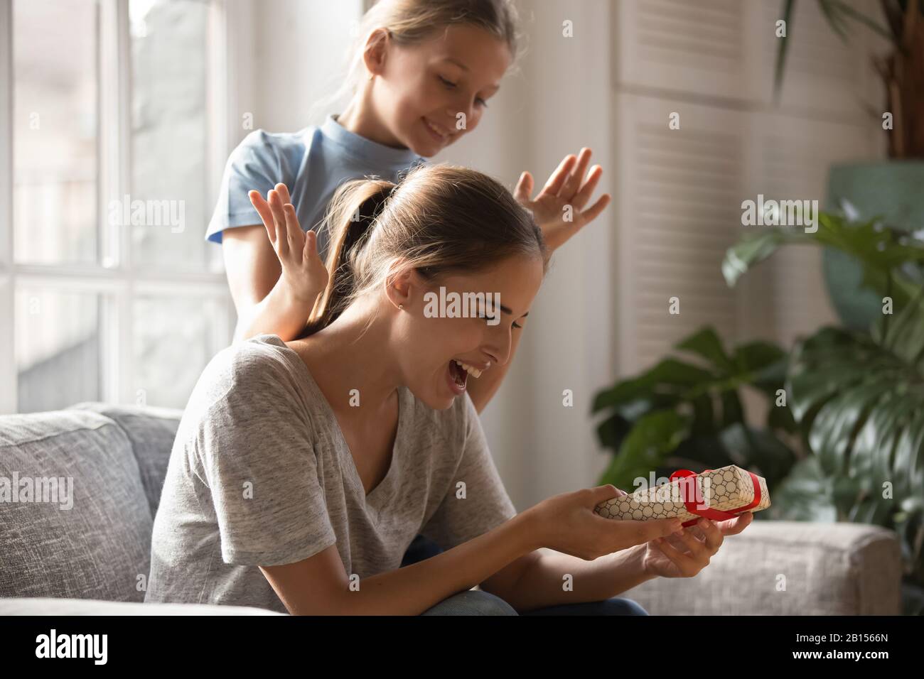 Smiling girl opened mommys eyes, giving present Stock Photo Alamy