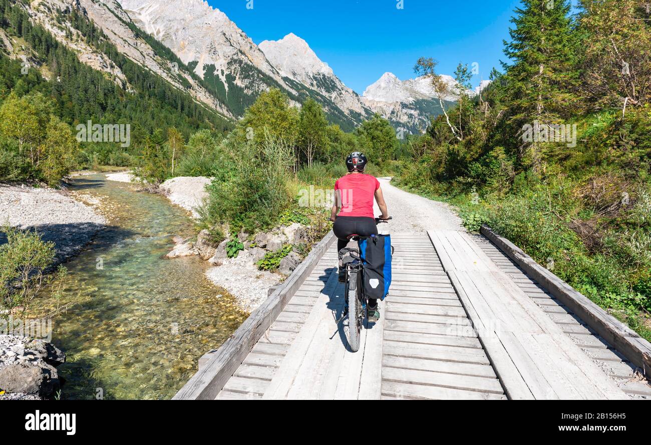 Cyclist, mountain biker bikes on bridge over mountain stream, gravel path to Karwendelhaus, Karwendeltal, Tyrol, Austria Stock Photo