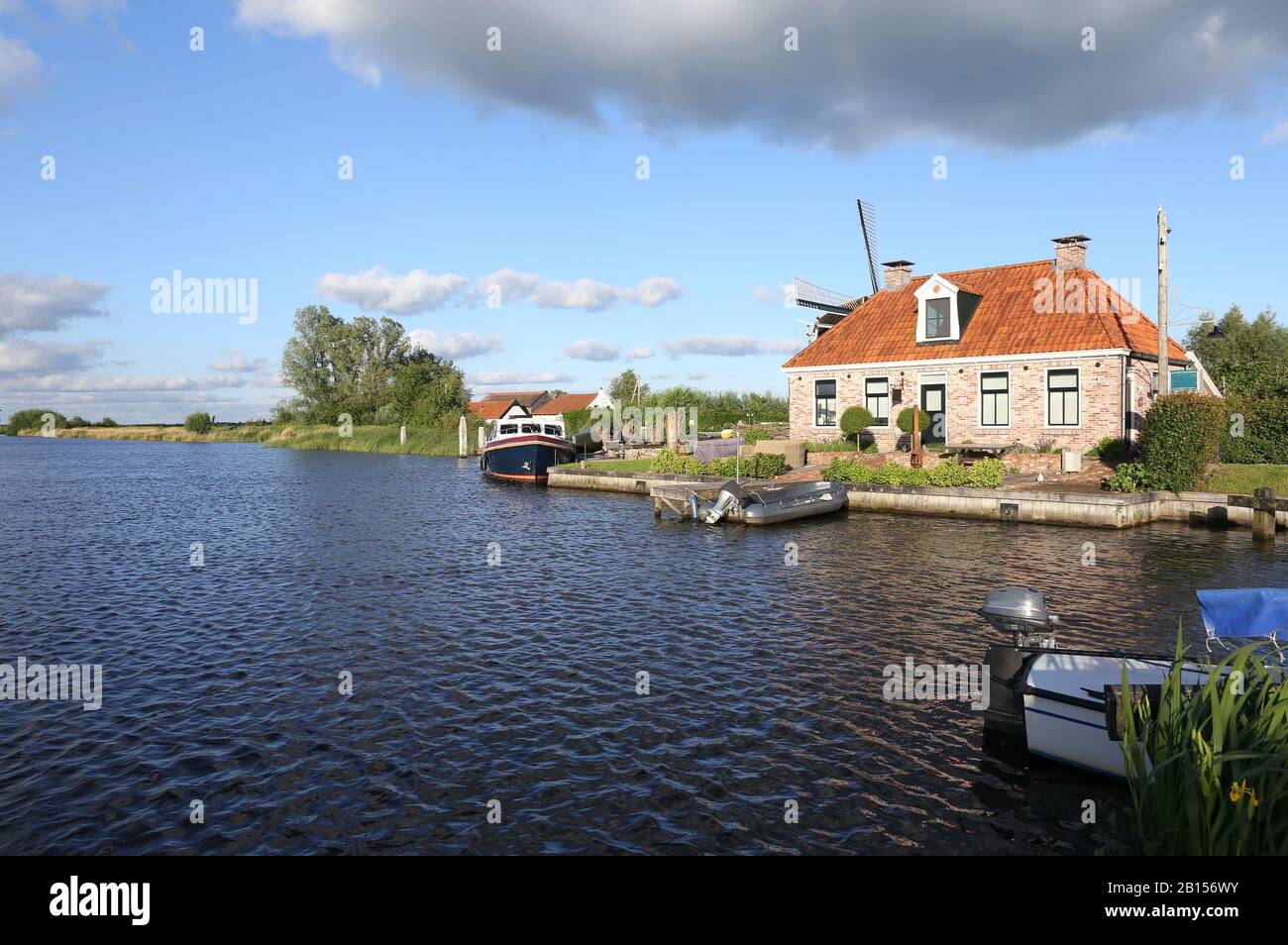 Canal with boats and a windmill near Scheenesluis in the Netherlands Stock Photo