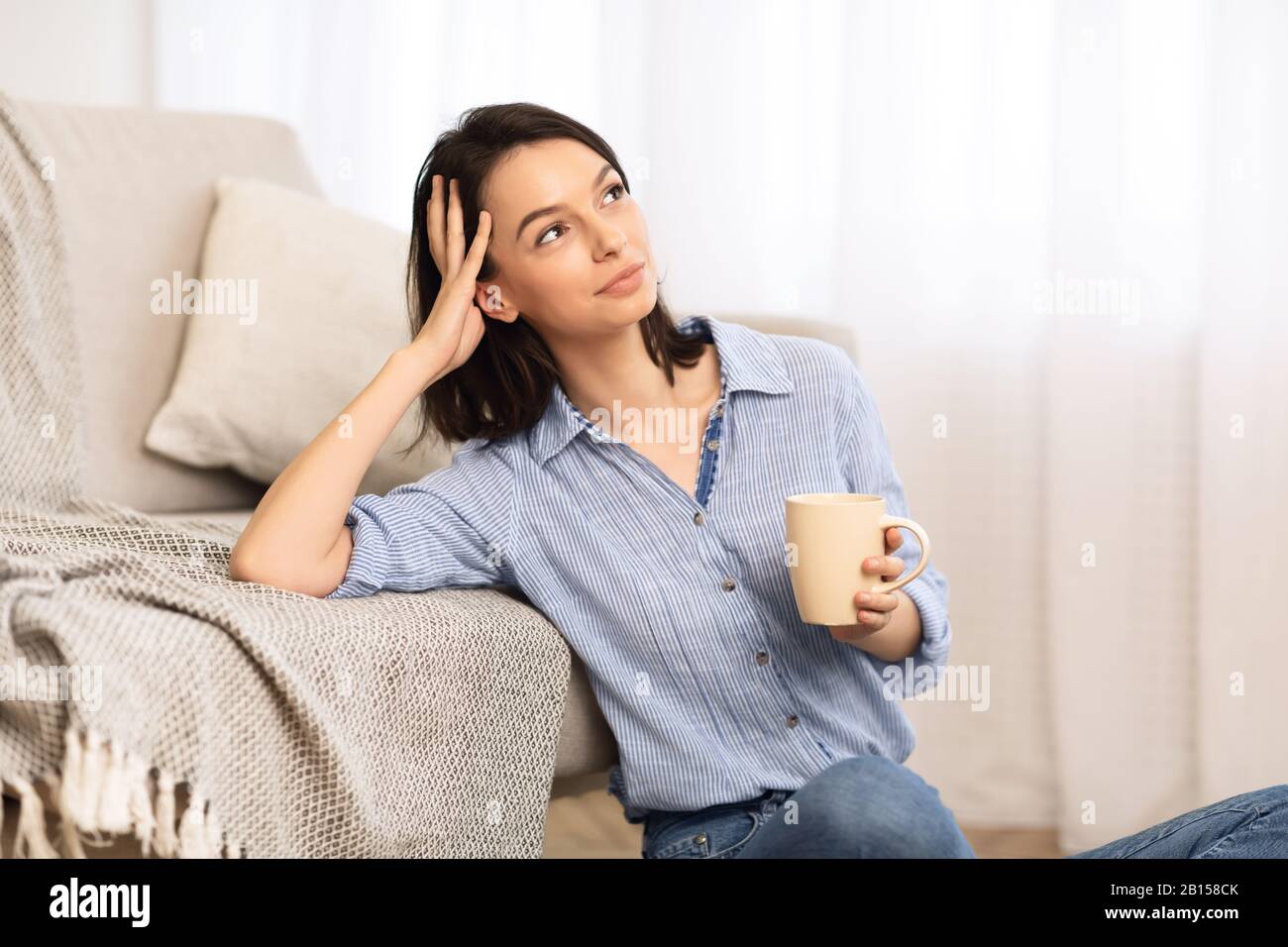 Cheerful young girl sitting on floor with cup of tea Stock Photo - Alamy