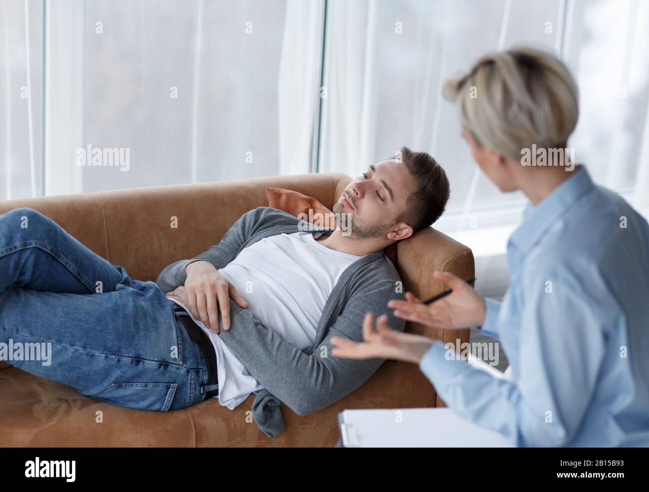 Patient Talking With Psychologist Lying On Couch In Office Stock Photo