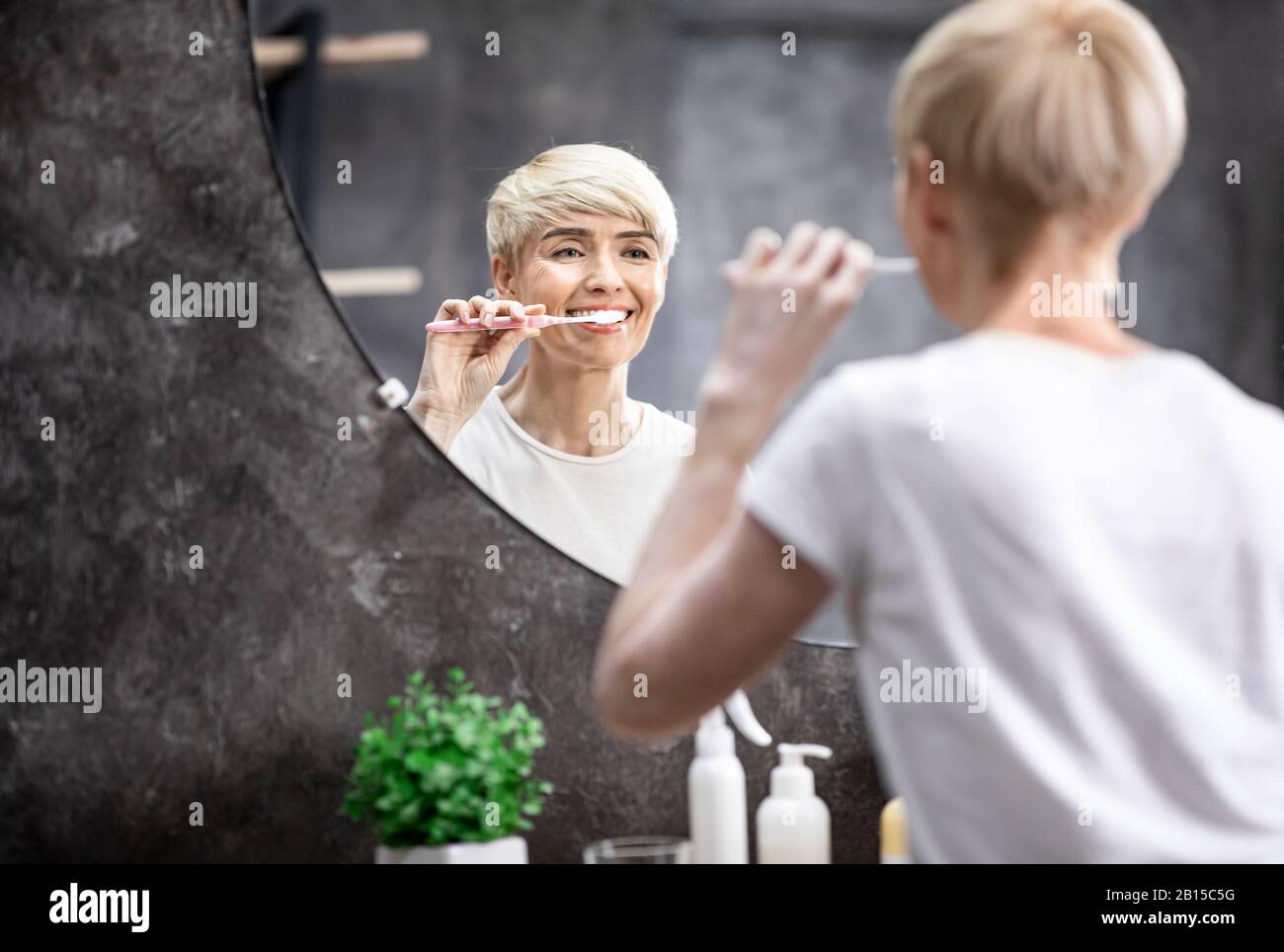 Lady Brushing White Teeth Standing In Bathroom In The Morning Stock Photo