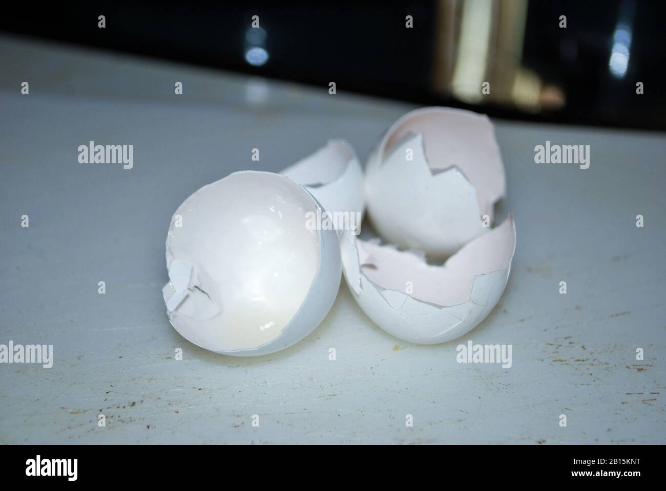 Close up of two cracked eggshells on a well used cutting board Stock Photo