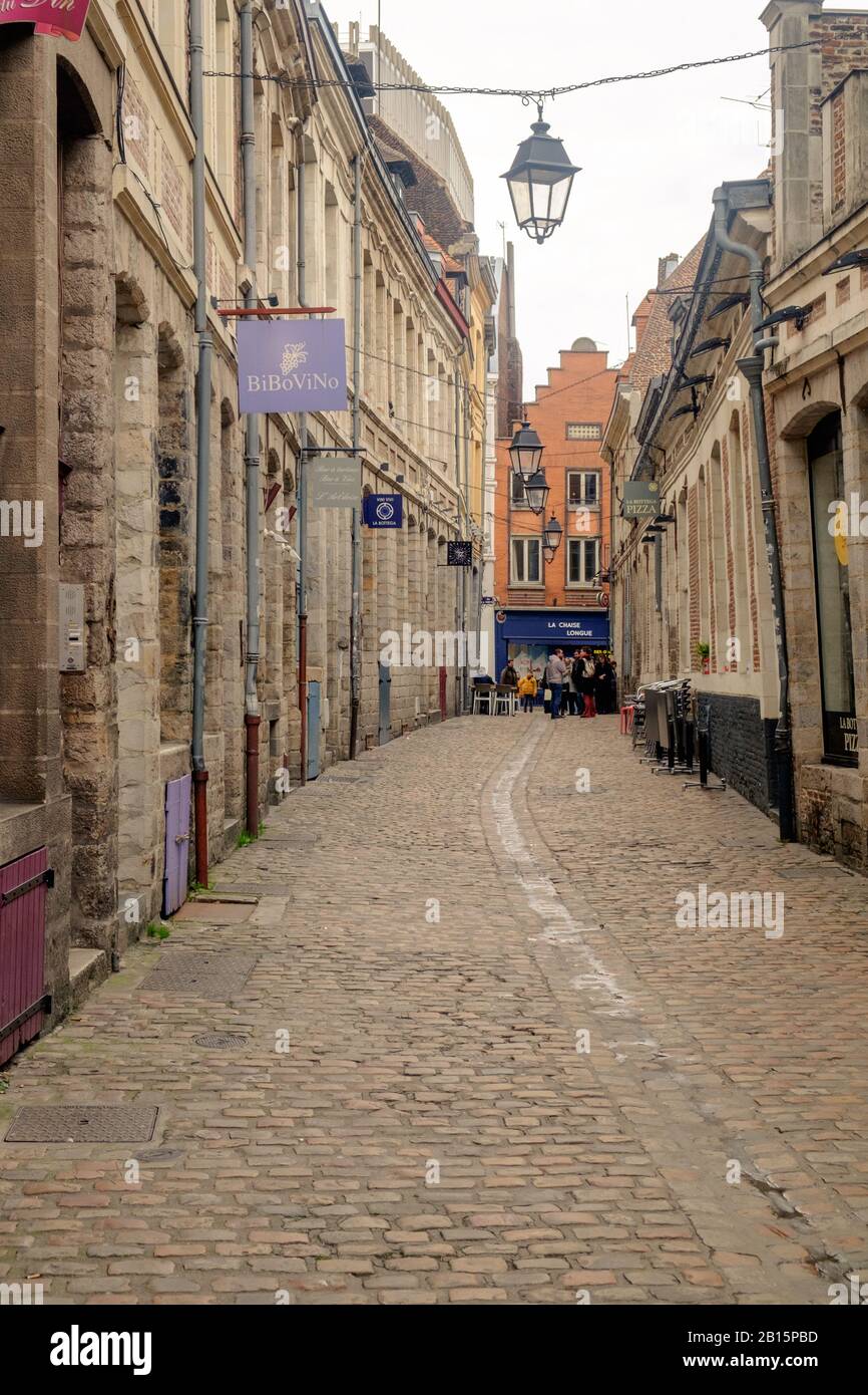 An empty street with cobblestones leads to a Flemish renaissance building in the Old Town of Lille. Stock Photo