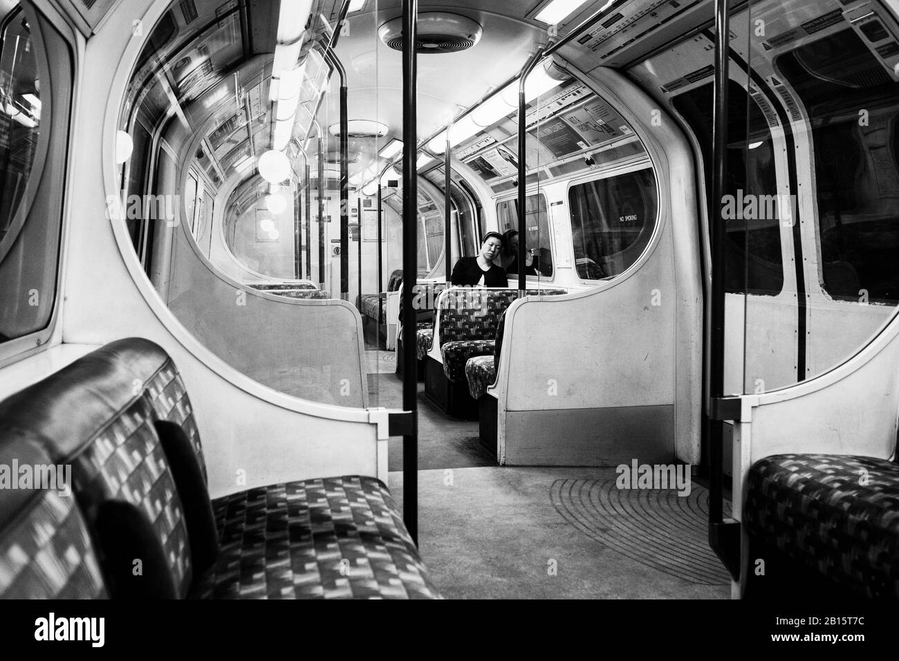 London black and white urban photography: Lone woman sleeping on Underground train, London, UK Stock Photo
