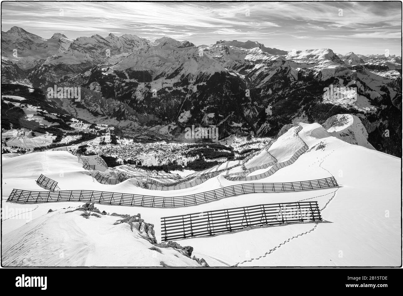 Black and white photo of avalanche protection barriers at the Männlichen, looking down to Wengen, Bernese Oberland, Switzerland Stock Photo