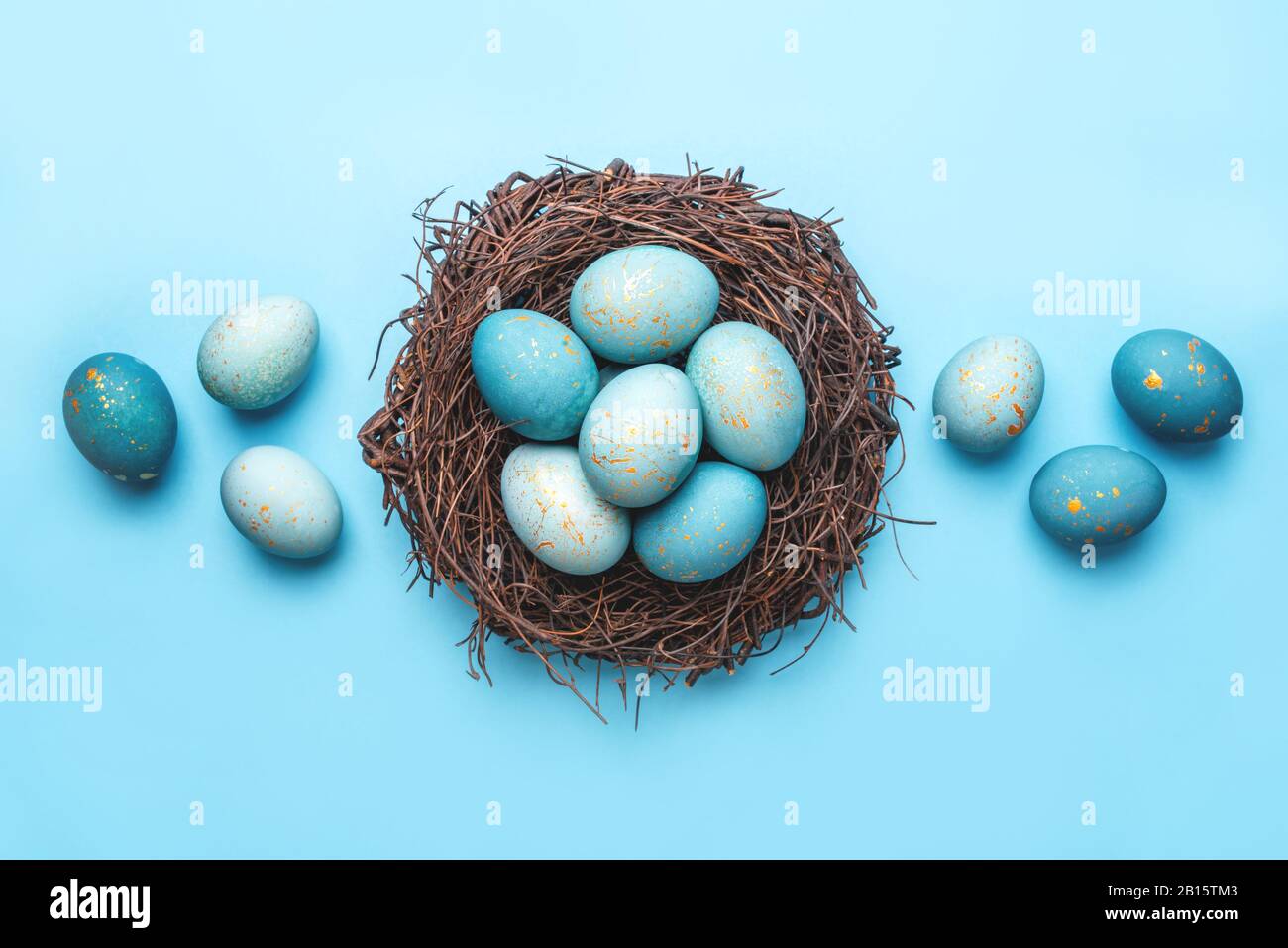 Easter eggs in nest on blue background Stock Photo - Alamy
