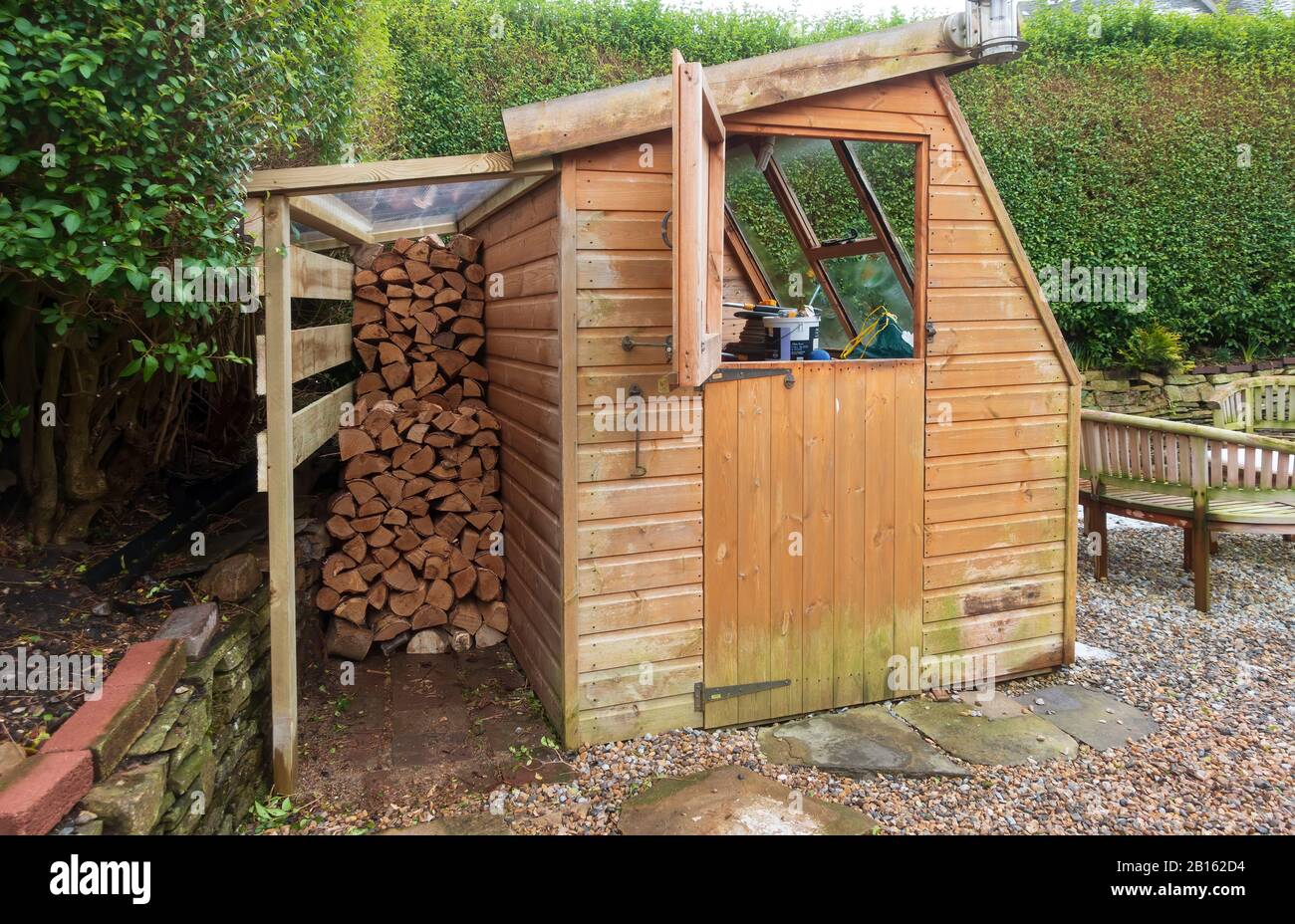 Garden shed with covered log pile Stock Photo