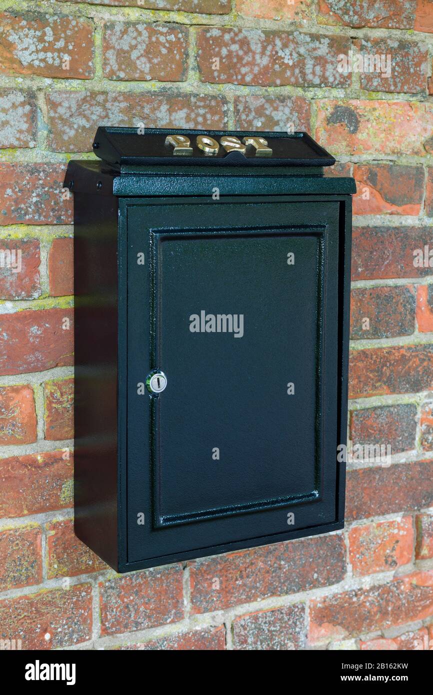 Vintage black post box or letterbox on a brick wall in England, UK Stock Photo