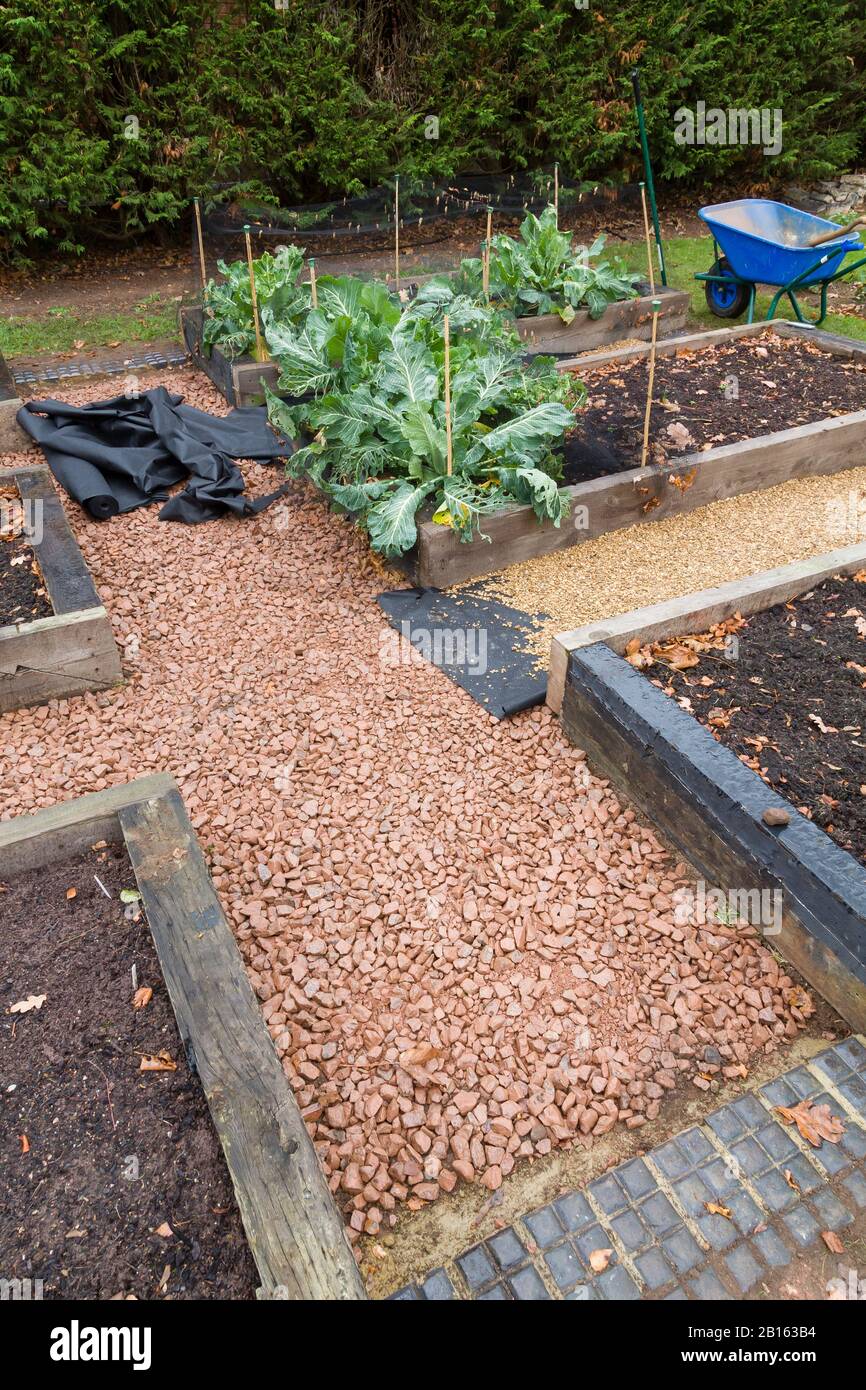 Installing weed control membrane or fabric and gravel pathway in a garden in England, UK Stock Photo