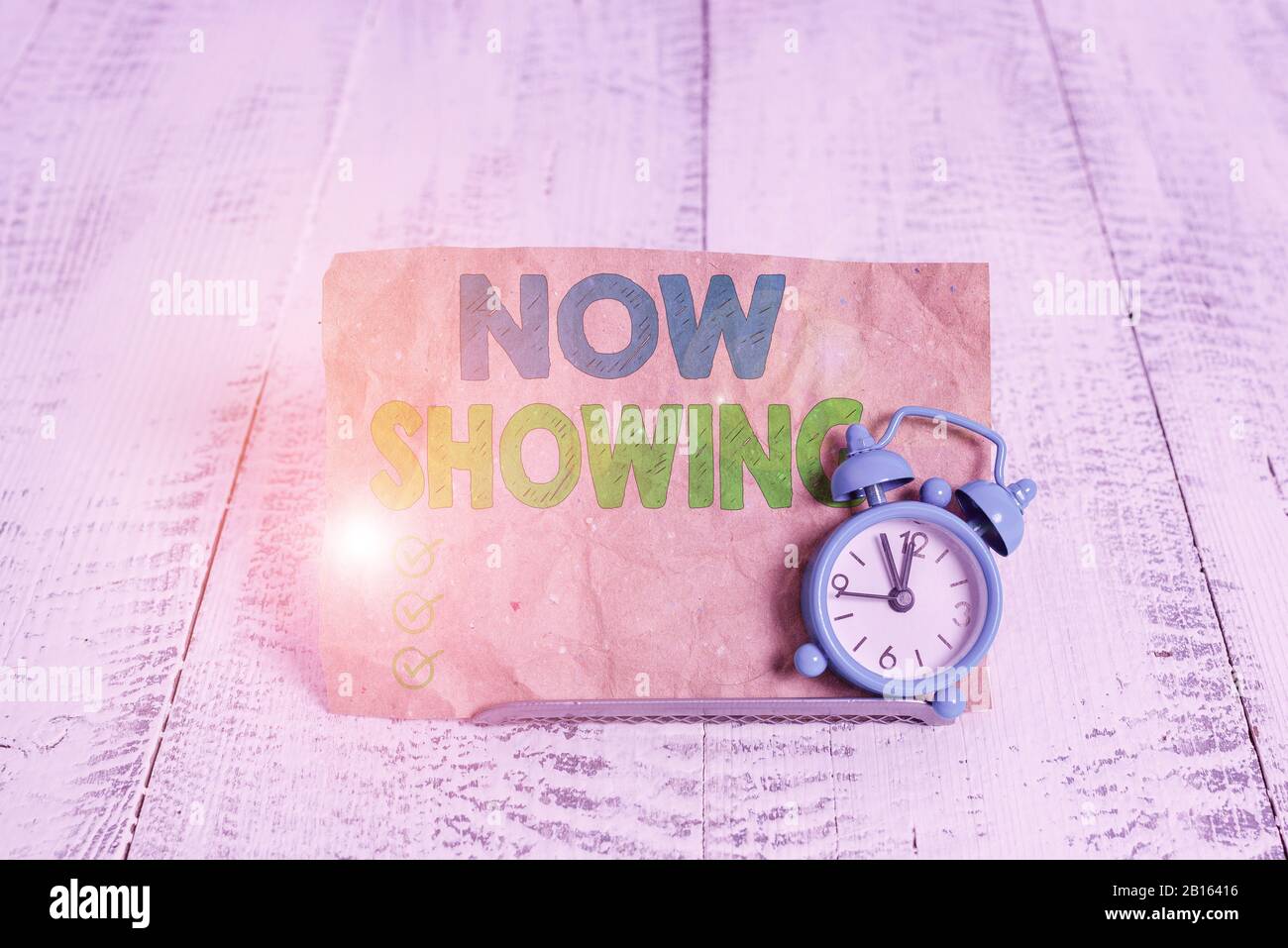 Handwriting text writing Now Showing. Conceptual photo opportunity for the public to see something currently available Mini blue alarm clock stand til Stock Photo