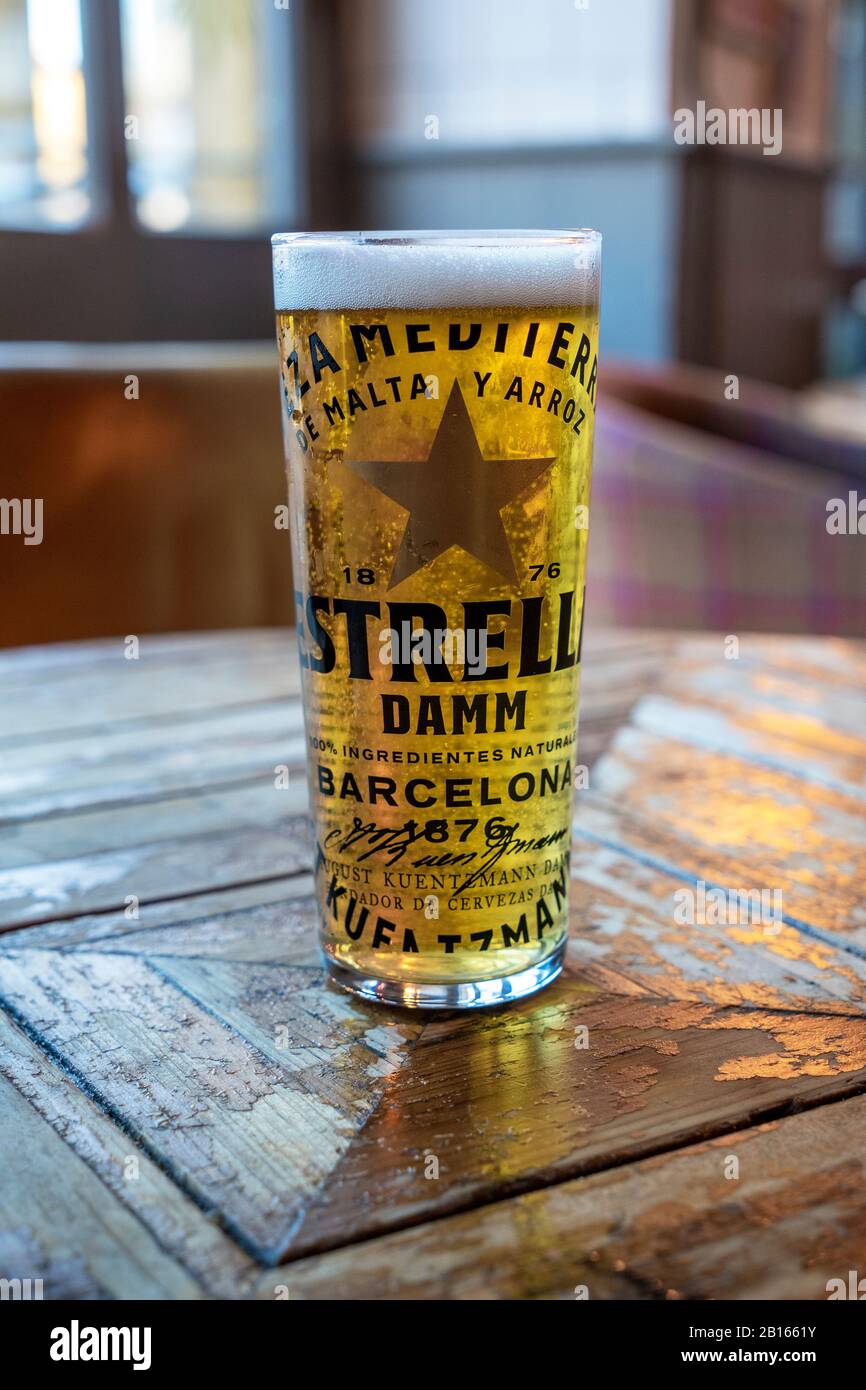 Pint glass of Estrella lager beer on a table lit from behind Stock Photo