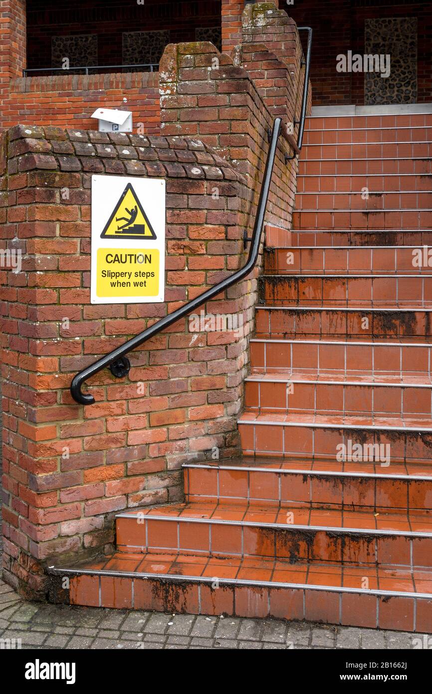 Caution slippery steps when wet sign next to wet steps Stock Photo