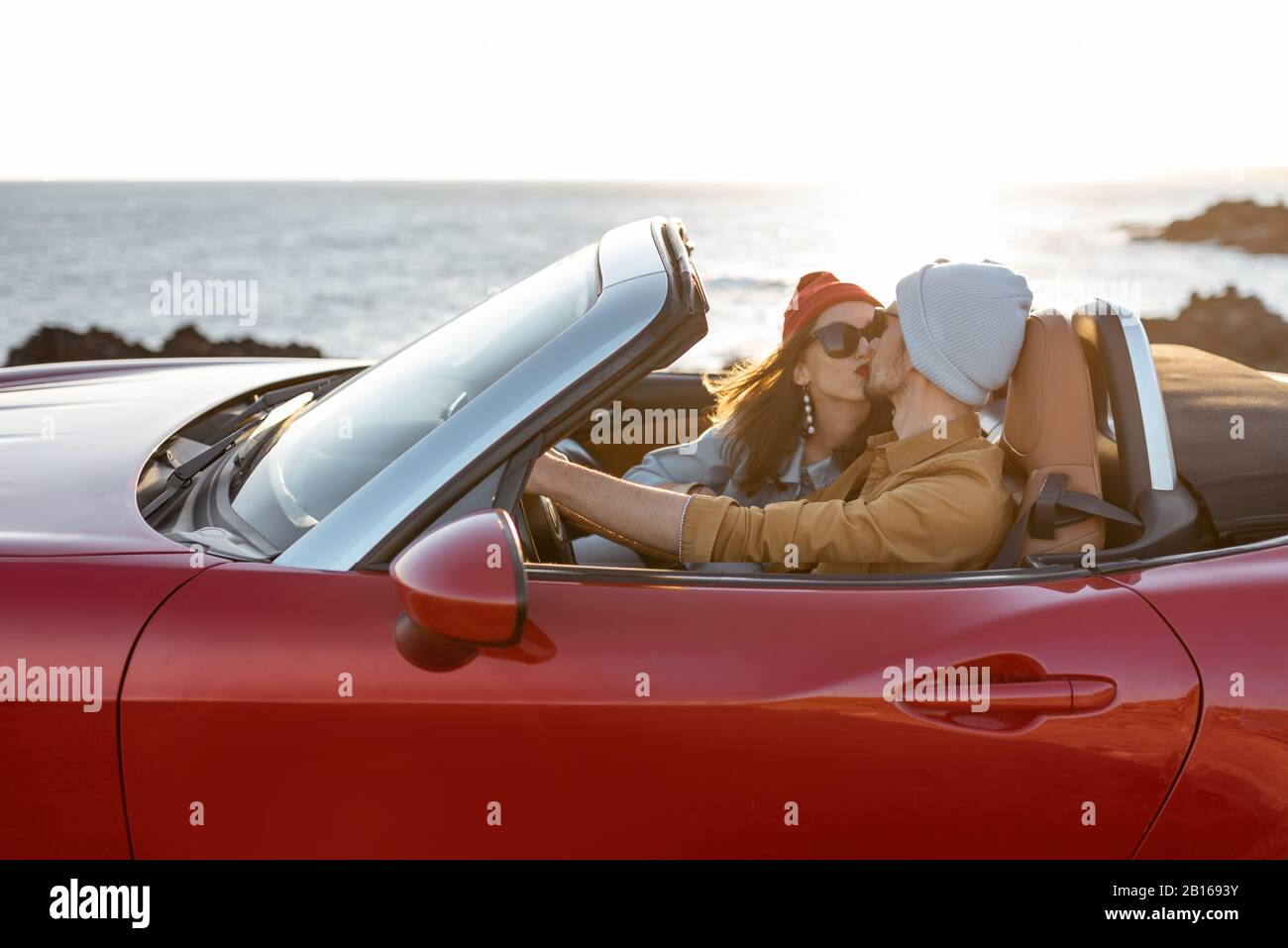 Joyful couple enjoying vacations, driving together convertible car on