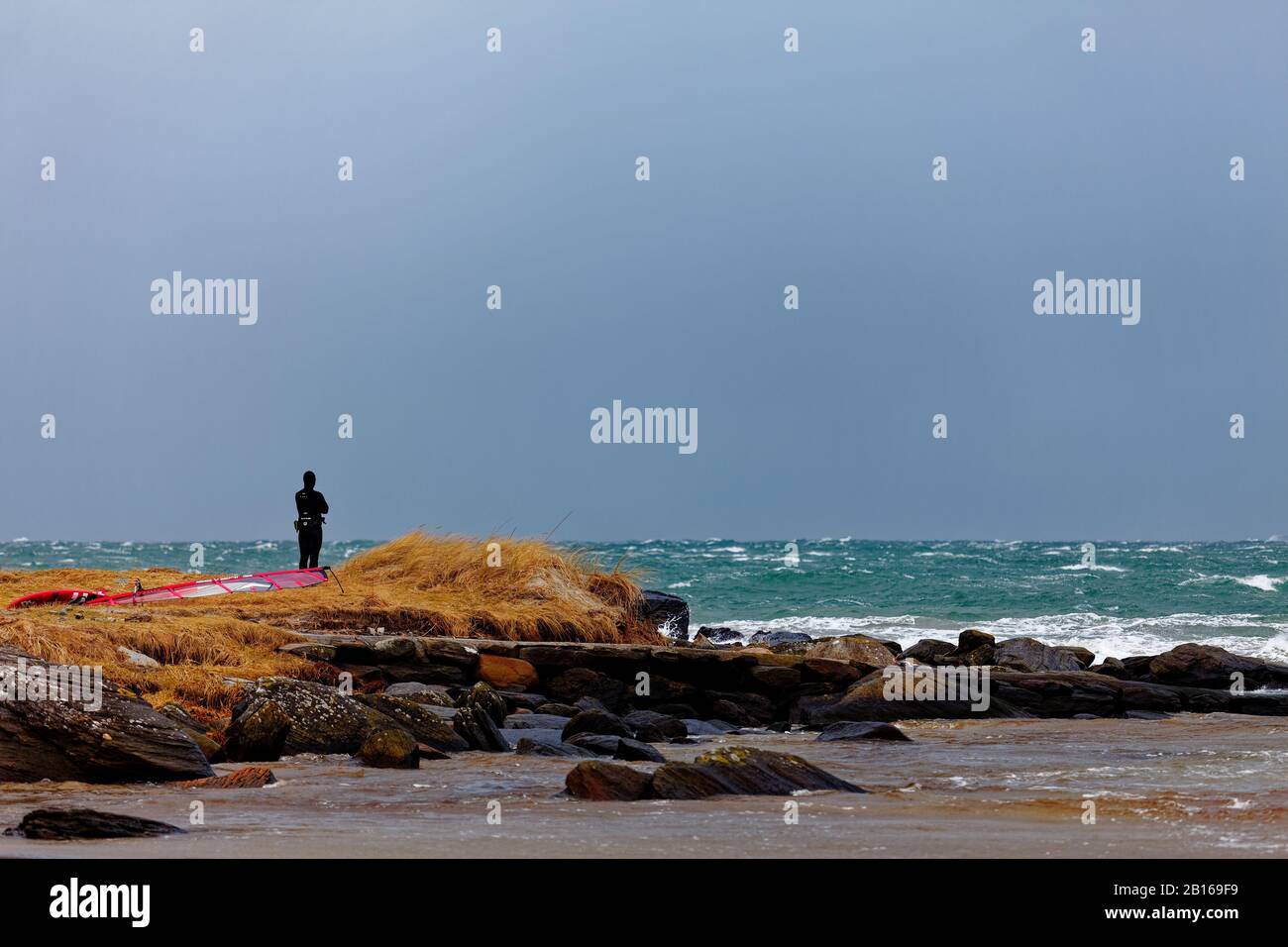 Wind surfer taking a break while watching the storm before getting back in the water Stock Photo