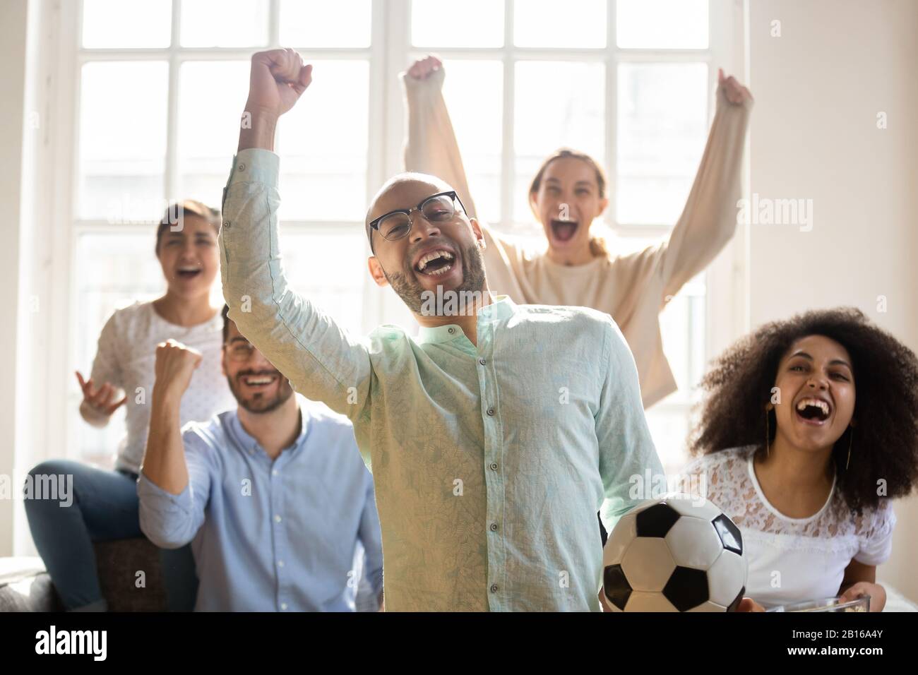 Mixed-race guy with friends enjoy favourite football team victory Stock Photo