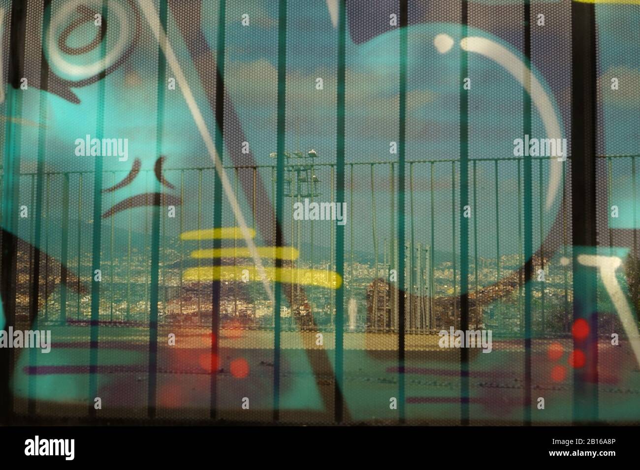 Graffiti on a transparent metal structure looking through to a view of Barcelona city Stock Photo