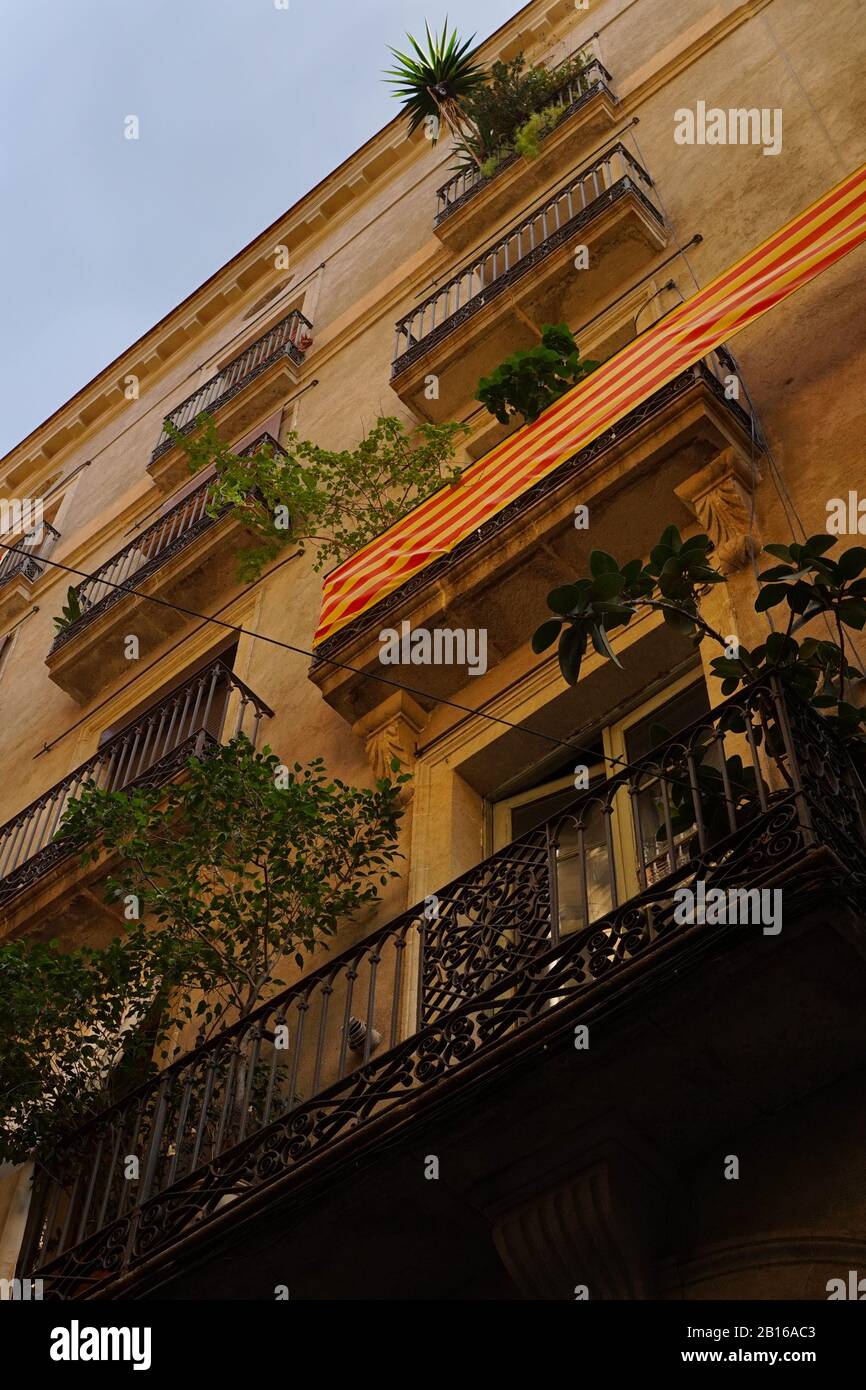 A view from below of a typical Spanish tall city building with balconies, plants & flags flying Stock Photo