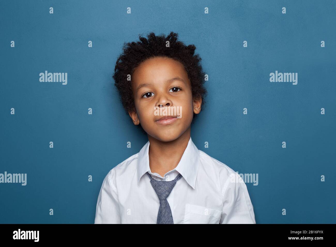 Portrait of cute little black child boy standing on blue background ...