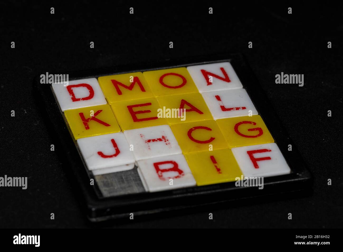 sliding letter game with red print on white and yellow tiles with black background stock photo alamy