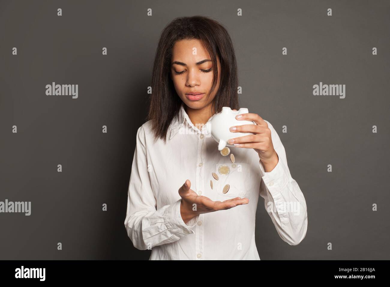 Sad student woman with coin and empty piggy bank Stock Photo - Alamy