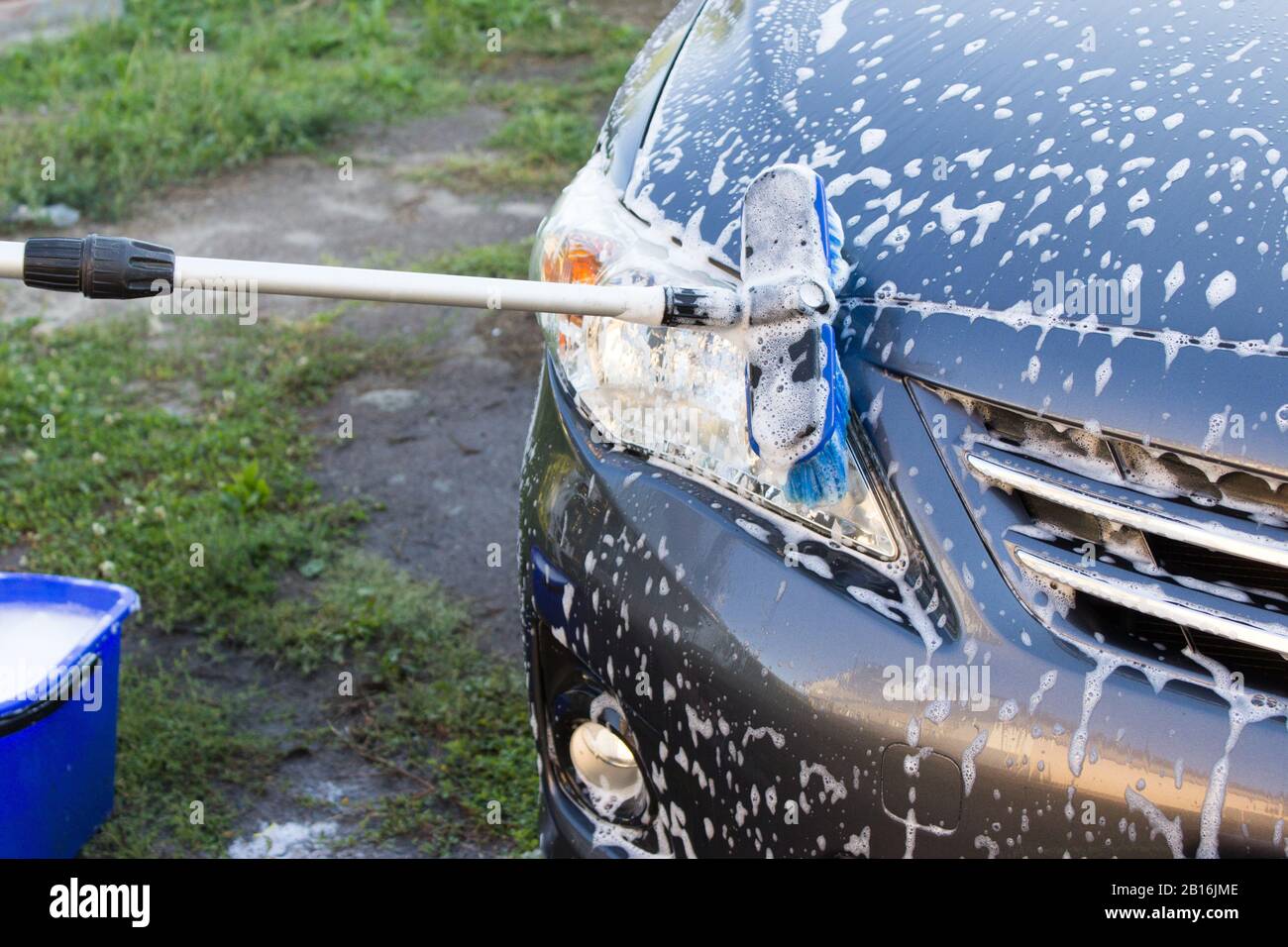 Concept of a car wash outdoor, washing a car with a brush with foam