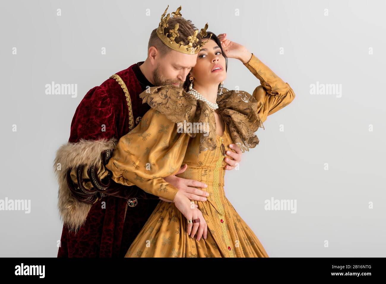 queen and smiling king with crowns holding hands isolated on grey