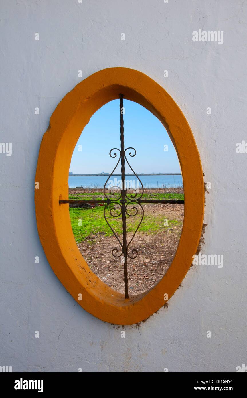 Oval orange window on the white wall overlooking the river bank, spring time. Spain Stock Photo