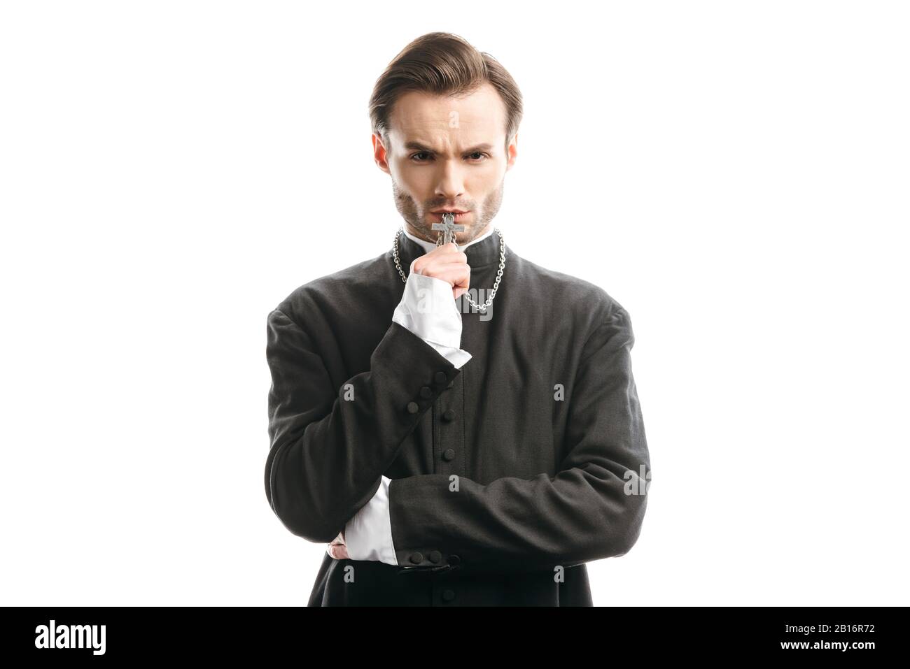 confident, serious catholic priest kissing holy cross while looking at
