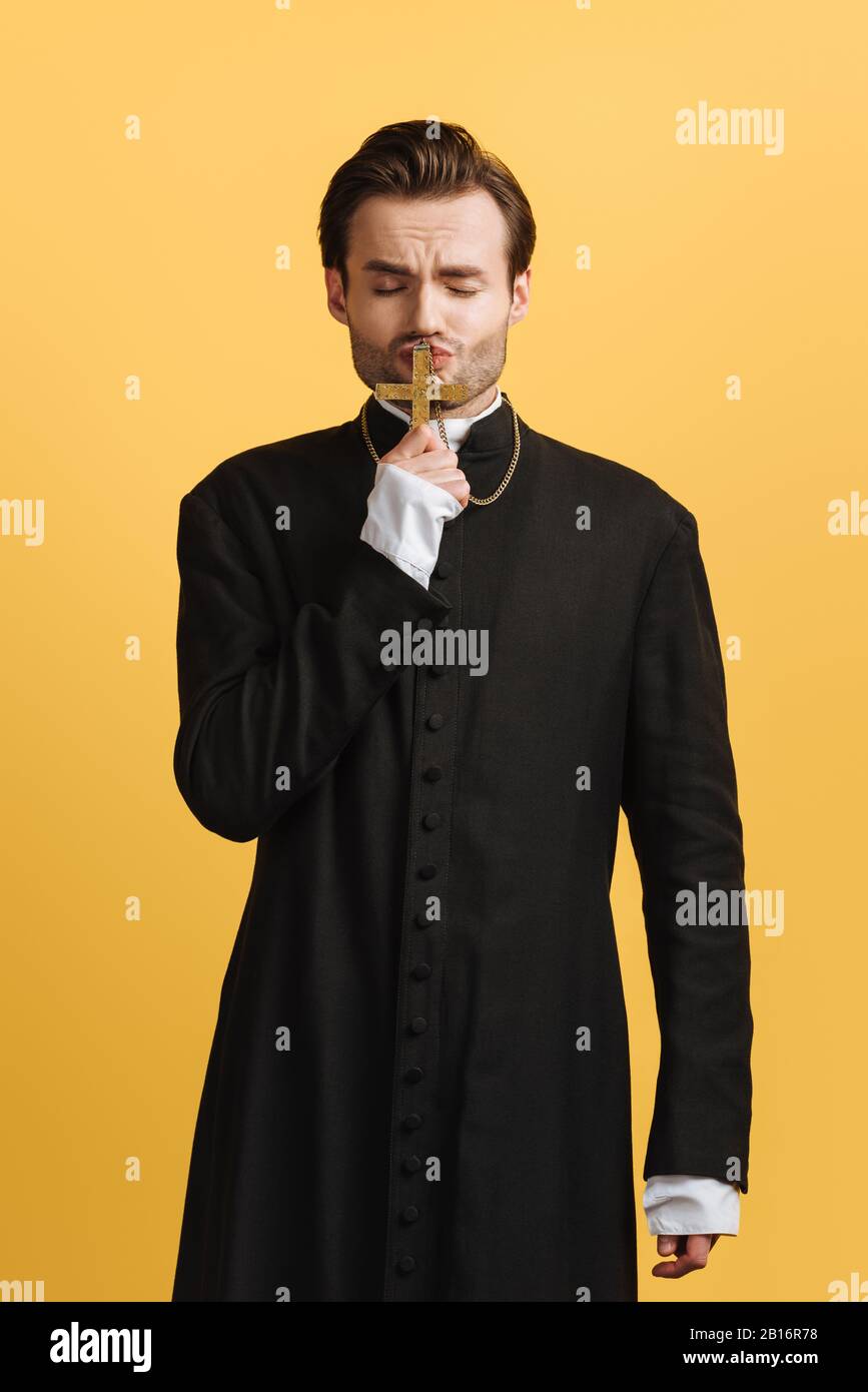 young faithful catholic priest kissing holy christ with closed eyes
