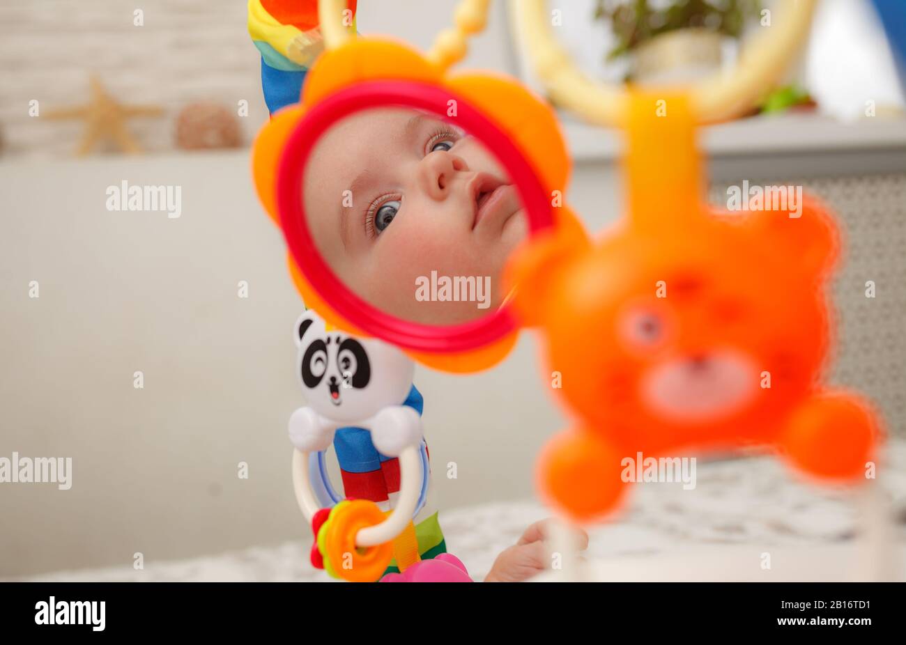 Baby sees his reflection in toy mirror on play mat. toys for newborns