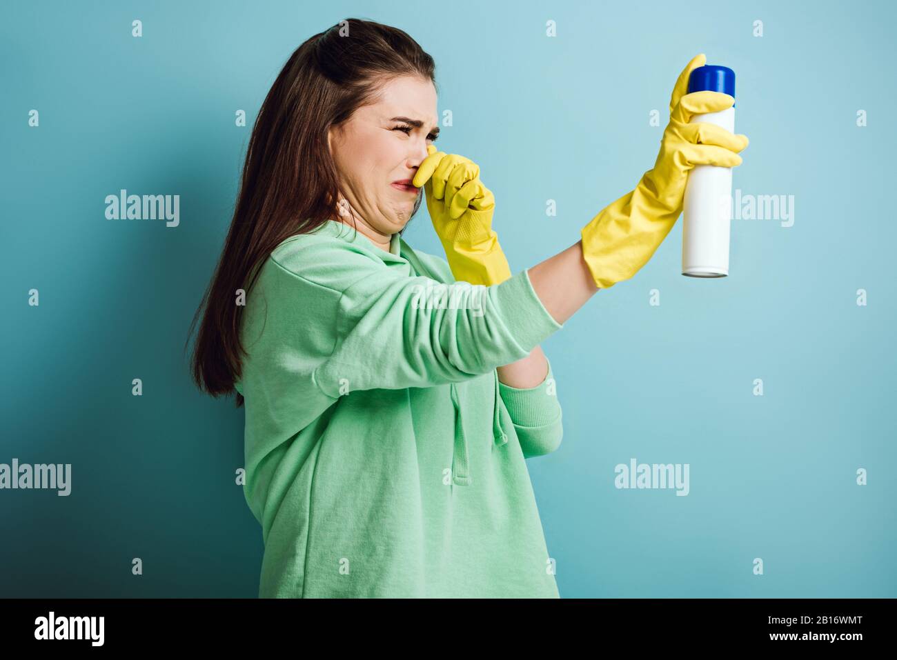 displeased housewife plugging nose with hand while spraying air