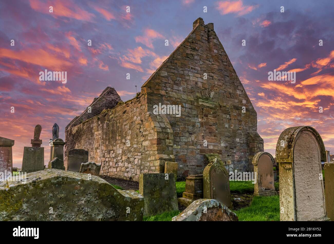 The Old Ruins of Prestwick Old Parish Church & Graveyard Rear ellevation taken agianst a Dramatic Red Sunset Sky. Stock Photo