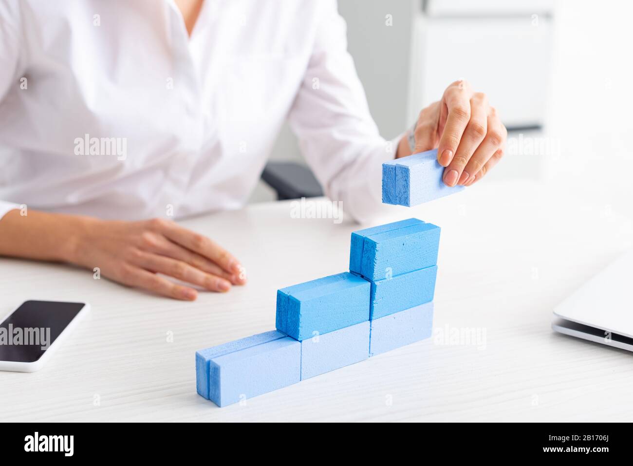 Selective focus of businesswoman stacking blue building blocks on table Stock Photo