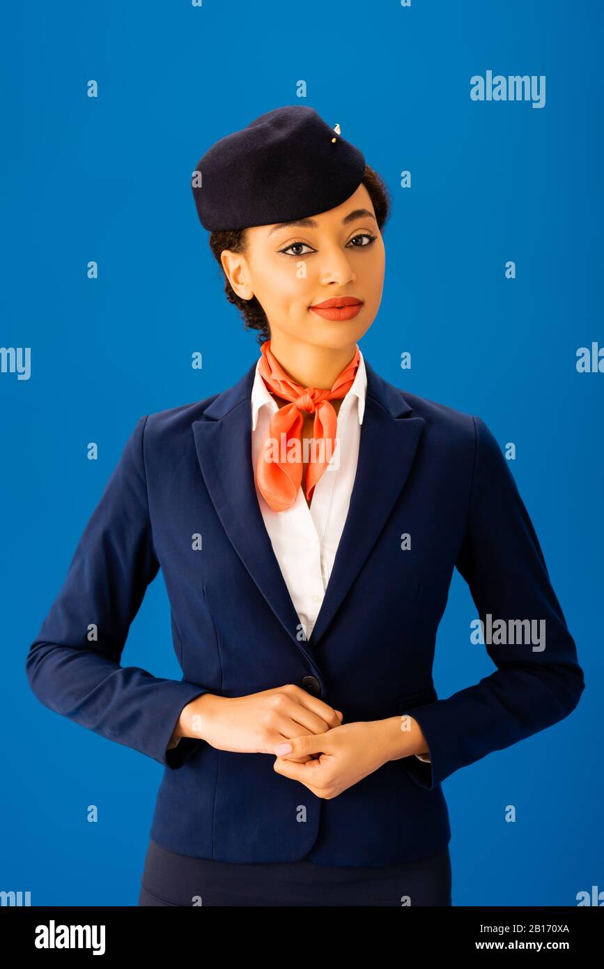 smiling african american flight attendant  looking at camera isolated on blue Stock Photo